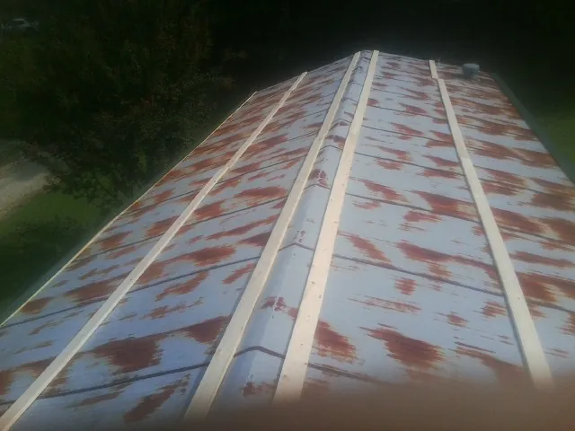 Rusted metal roof panels with new wood purlins before replacement — Storm Damage Roof Repair in Coats by Roofing Brothers