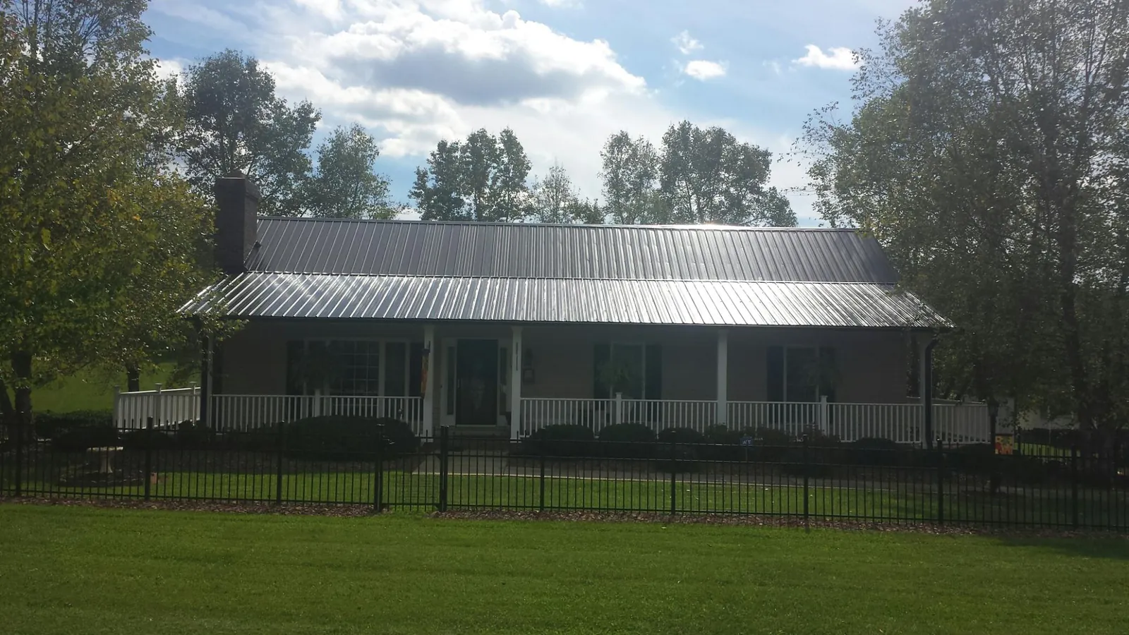 Gray metal roof on a brick ranch with a full width front porch — Gutter Guard Installation work by our crew in Coats