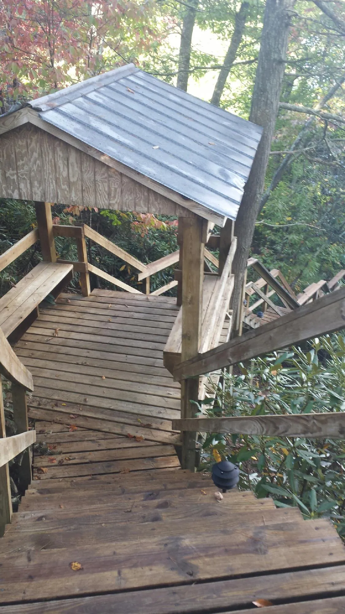 Metal roofed shelter over wooden steps on a wooded walkway — Skylight Repair & Installation work by our crew in Coats